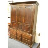 A large George III and later oak cupboard, the integral cornice above twin panelled doors, the