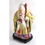 A 20th century Chinese figure of an immortal holding a peach, on stand (2)