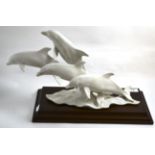 A large Kaiser parian group of four leaping dolphins on hardwood plinth