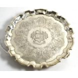 A George III silver waiter, chased with a family crest, scrolls and flowers and raised on three