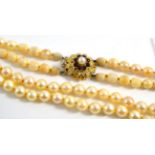 A two row cultured pearl necklace with a garnet clasp, stamped '9CT' (a.f.)