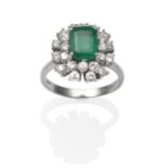 An 18 Carat White Gold Emerald and Diamond Cluster Ring, an emerald-cut emerald within a two tier