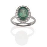 An 18 Carat White Gold Emerald and Diamond Cluster Ring, an oval cut emerald within a border of