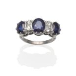 A Sapphire and Diamond Ring, three graduated oval mixed cut sapphires spaced by pairs of diamonds in