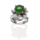 A Jade Ring, a round cabochon jade in a white four claw setting within a textured leaf spray, on a