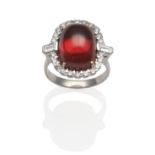 An 18 Carat White Gold Garnet and Diamond Cluster Ring, an oval cabochon garnet within a border of