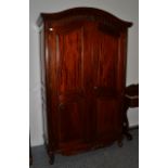 A Reproduction Hardwood Wardrobe, the domed and moulded pediment above two panel doors enclosing