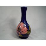 A Moorcroft Pottery solifleur vase decorated with pink magnolia on a cobalt blue ground,