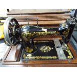 A vintage hand cranked Singer sewing machine No 28 with various attachments and a copy of