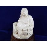 A 19th century highly carved ivory figure depicting a Buddha on a wooden plinth, approximately 9.