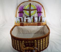 A wicker basket picnic set containing cu