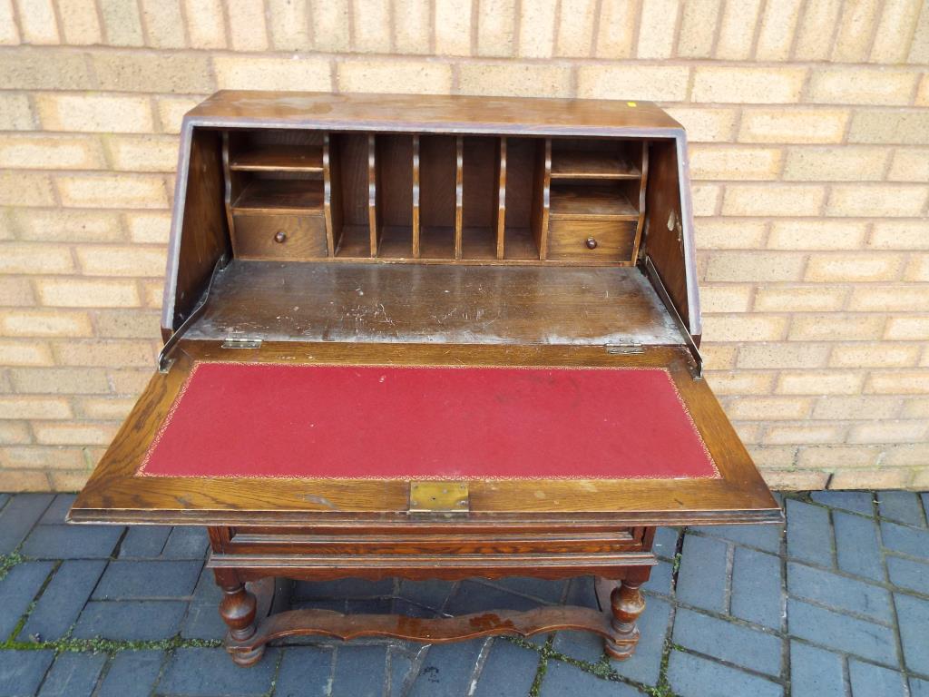 An oak bureau, the slope front opening to reveal a pigeon-hole fitted interior above two drawers,