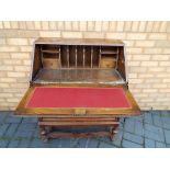 An oak bureau, the slope front opening to reveal a pigeon-hole fitted interior above two drawers,