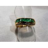 A lady’s 18ct gold ring marked 750 with baguette cut emeralds and diamonds forming a half eternity,