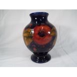Moorcroft Pottery - a baluster vase decorated with pomegranate on a cobalt blue ground,