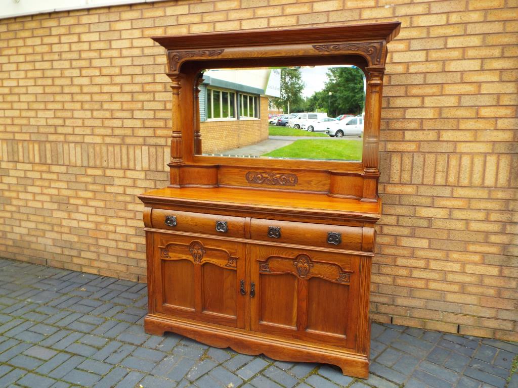 An Art Nouveau oak, mirror-backed sideboard with decorative carving,