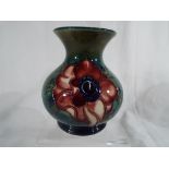 Moorcroft Pottery - a small vase decorated with anemone on a green ground,