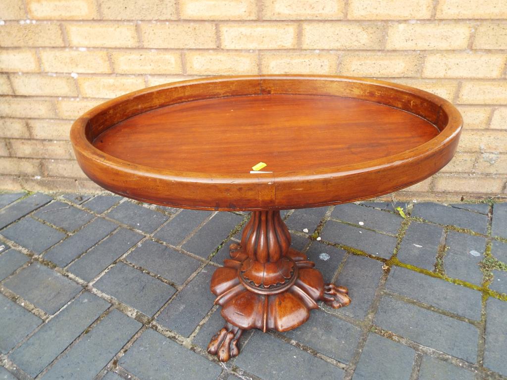 A mahogany, oval pedestal table on turned support terminating in claw feet.