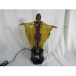 An Art Deco style lamp in the form of a lady with a green and yellow cloak,
