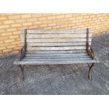 An early 20th century garden bench with wooden slatted seat and wrought iron ends,
