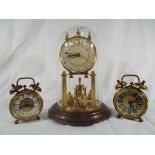 A brass anniversary clock under glass dome together with two alarm clocks,