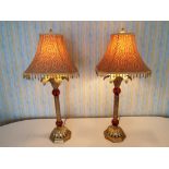 A matched pair of good quality gilded metal and amber glass table lamps with shades,