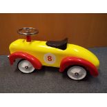 A child's push-along car, red and yellow, unused,