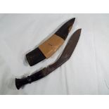 A kukri knife with steel tipped leather scabbard