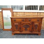 An oak Arts and Crafts carved-fronted sideboard and an oak framed bevel edged mirror (2) - Est £20