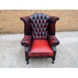 A red leather Chesterfield wing back armchair - Est £60 - £100