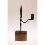 A WROUGHT IRON RUSHNIP, the arm with candle holder, mounted in an oak block.