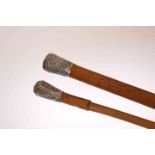 TWO WALKING STICKS WITH CHINESE WHITE METAL HANDLES, the first decorated with figures,