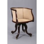 AN EARLY 20TH CENTURY BEECH AND CANEWORK SWIVELLING DESK CHAIR, with hoop back, moving on castors.