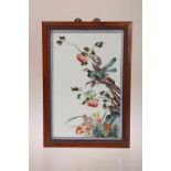 A CHINESE PORCELAIN PANEL, decorated in enamels with two birds on a branch amongst foliage,