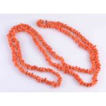 A CORAL NECKLACE, the multi irregular shaped coral beads strung simply as one long row.