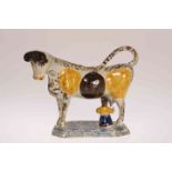 AN EARLY 19TH CENTURY PEARLWARE COW CREAMER, of characteristic form with sponged decoration. 13.