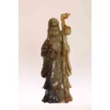 A CHINESE SERPENTINE CARVING OF SHOU LAO, carved standing holding a staff and a sprig of foliage.