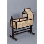 A 19TH CENTURY CANEWORK CRADLE ON STAND, with pointed arch hood, the stand with turned stretchers.