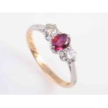 A RUBY AND DIAMOND RING, the oval cut ruby six claw set between two brilliant cut claw set diamonds,