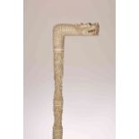 A CHINESE CARVED IVORY PARASOL HANDLE, with dragon head and intricately carved stem with figures,