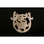 A JADE PENDANT, pierced and carved with a dragon to the centre, of a white colour with green tinge,