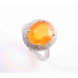 AN ORANGE SAPPHIRE AND DIAMOND RING, the oval cut orange sapphire four claw set,