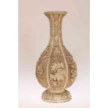 A CHINESE IVORY COLOURED LACQUER VASE, of lobed baluster form, decorated in relief with foliage.