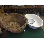 A wicker log basket and an enamelled miniature bath and bowl