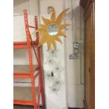 A contemporary wooden sun burst mirror and a piece of metal wall art