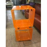 A pair of orange plastic cube trolleys