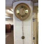 A circular oak wall clock with sun burst pendulum