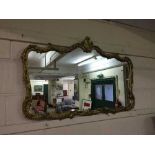 A decorative gilt metal over mantel mirror