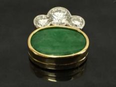 An 18ct gold jade and diamond pendant, the oval jade stone surmounted by three diamonds,