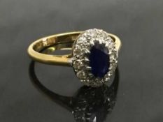 An 18ct gold sapphire and platinum set diamond cluster ring, size P.